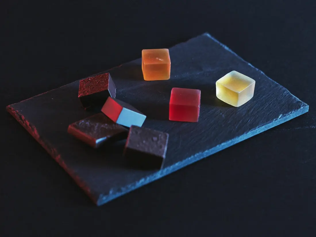 Chocolate squares and fruit gummies arranged on a dark slate board